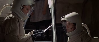 Movie still from “The Andromeda Strain” (1971), directed by Robert Wise – Two people in protective gear are on a train; Medium shot, Over the shoulder angle