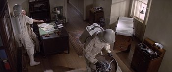 Movie still from “The Andromeda Strain” (1971), directed by Robert Wise – A person in a suit and helmet is standing in a room; Wide shot, High angle