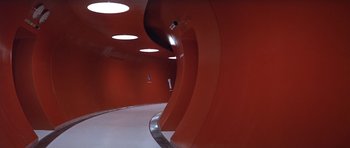 Movie still from “The Andromeda Strain” (1971), directed by Robert Wise – A hallway with a red wall and a curved metal floor; Extreme Wide shot, High angle