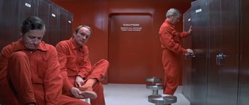 Movie still from “The Andromeda Strain” (1971), directed by Robert Wise – Two men in red jumpsuits are sitting in a room; Wide shot, Low angle
