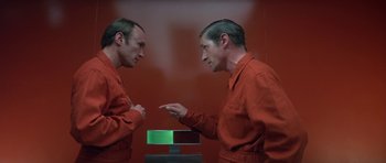 Movie still from “The Andromeda Strain” (1971), directed by Robert Wise – A man in a red prison suit is looking at himself in the mirror; Medium shot, Over the shoulder angle