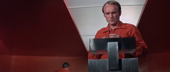 Movie still from “The Andromeda Strain” (1971), directed by Robert Wise – A man in a red shirt is looking at his cell phone; Medium shot, Low angle