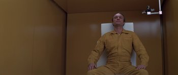 Movie still from “The Andromeda Strain” (1971), directed by Robert Wise – A man sitting on a chair in an orange room; Medium shot, Low angle
