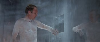Movie still from “The Andromeda Strain” (1971), directed by Robert Wise – A man in a white shirt and white gloves is in a shower; Medium shot, Low angle