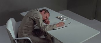 Movie still from “The Andromeda Strain” (1971), directed by Robert Wise – A man sleeping on top of a book on top of a table; Medium shot, High angle