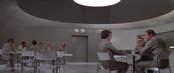 Movie still from “The Andromeda Strain” (1971), directed by Robert Wise – A group of people sitting at a table in a room; Wide shot, Over the shoulder angle