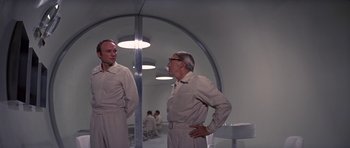 Movie still from “The Andromeda Strain” (1971), directed by Robert Wise – Two men are standing next to each other in a room; Medium shot, Low angle