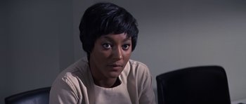 Movie still from “The Andromeda Strain” (1971), directed by Robert Wise – A woman sitting at a table looking at the camera; Close Up shot, Over the shoulder angle