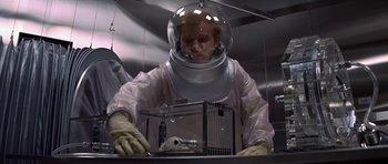 Movie still from “The Andromeda Strain” (1971), directed by Robert Wise – A man in a space suit is working in a lab; Medium shot, Low angle