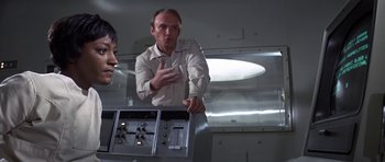 Movie still from “The Andromeda Strain” (1971), directed by Robert Wise – A man standing next to another man in a room; Medium shot, Low angle