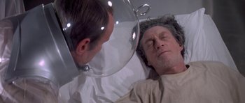 Movie still from “The Andromeda Strain” (1971), directed by Robert Wise – A man is lying in a hospital bed with a mirror; Close Up shot, High angle