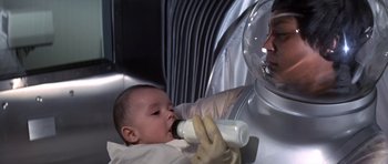 Movie still from “The Andromeda Strain” (1971), directed by Robert Wise – A baby is being fed a bottle by a person; Close Up shot, High angle