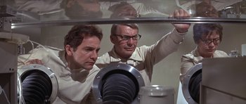 Movie still from “The Andromeda Strain” (1971), directed by Robert Wise – Two men are looking at something in a mirror; Medium shot, Low angle