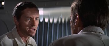 Movie still from “The Andromeda Strain” (1971), directed by Robert Wise – A man talking to another man in front of a curtain; Close Up shot, Over the shoulder angle