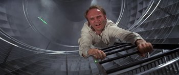 Movie still from “The Andromeda Strain” (1971), directed by Robert Wise – A man in white shirt and black tie leaning on a railing; Medium shot, Overhead angle