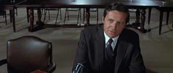 Movie still from “The Andromeda Strain” (1971), directed by Robert Wise – A person wearing a suit and tie; Close Up shot, Over the shoulder angle