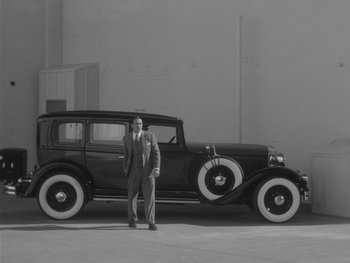 Movie still from “The Artist” (2011), directed by Michel Hazanavicius – A man standing in front of an old car; Wide shot, Low angle