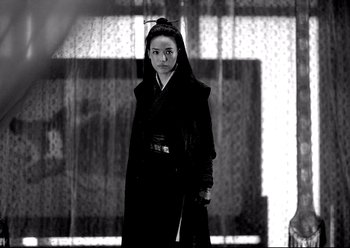 Movie still from “The Assassin” (2015), directed by Hsiao-Hsien Hou – A woman in a black coat standing next to a window; Medium shot, Over the shoulder angle