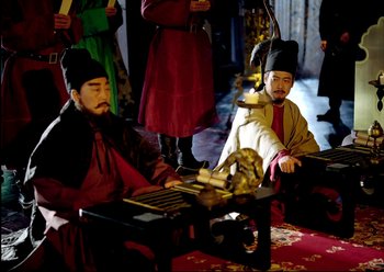Movie still from “The Assassin” (2015), directed by Hsiao-Hsien Hou – A couple of men sitting next to each other on a table; Wide shot, High angle