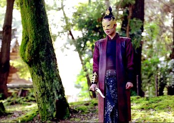Movie still from “The Assassin” (2015), directed by Hsiao-Hsien Hou – A person with a mask holding a knife in a forest; Medium shot, Low angle