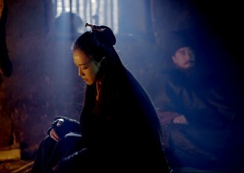 Movie still from “The Assassin” (2015), directed by Hsiao-Hsien Hou – A woman sitting in a dark room next to a man; Medium shot, Over the shoulder angle