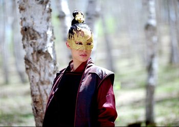 Movie still from “The Assassin” (2015), directed by Hsiao-Hsien Hou – A woman wearing a mask standing next to a tree; Close Up shot, Over the shoulder angle
