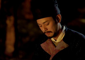 Movie still from “The Assassin” (2015), directed by Hsiao-Hsien Hou – A man wearing a black hat is looking down at his face; Close Up shot, Low angle