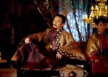 Movie still from “The Assassin” (2015), directed by Hsiao-Hsien Hou – A man sitting on top of a chair wearing a robe; Medium shot, Low angle