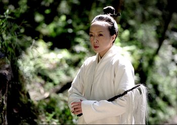 Movie still from “The Assassin” (2015), directed by Hsiao-Hsien Hou – A woman dressed in a white outfit holding a black stick in her hands; Medium shot, Low angle