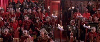 Movie still from “The Baby of Mâcon” (1993), directed by Peter Greenaway – A group of people sitting in a room with lit candles; Wide shot, High angle