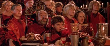 Movie still from “The Baby of Mâcon” (1993), directed by Peter Greenaway – A group of people sitting at a table with food; Medium shot, High angle