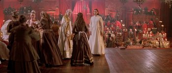 Movie still from “The Baby of Mâcon” (1993), directed by Peter Greenaway – A group of people standing on a wooden floor in front of a crowd; Wide shot, Low angle