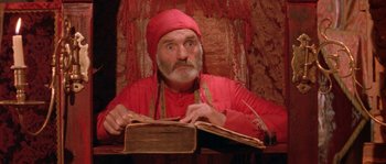 An old man sitting at a table with an open book