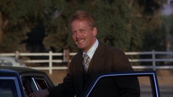 Movie still from “The Bad News Bears” (1976), directed by Michael Ritchie – A man in a suit and tie smiling for the camera; Close Up shot, Low angle