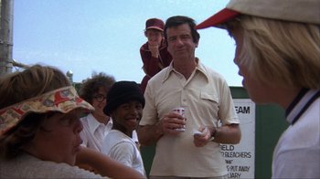 Movie still from “The Bad News Bears” (1976), directed by Michael Ritchie – An older man holding a can of soda in front of a group of people; Medium shot, Over the shoulder angle