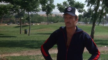 Movie still from “The Bad News Bears” (1976), directed by Michael Ritchie – A man in a baseball cap stands in a park; Medium shot, Low angle