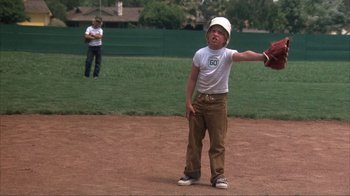Movie still from “The Bad News Bears” (1976), directed by Michael Ritchie – A young boy holding a catchers mitt on top of a field; Medium shot, Low angle