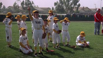 Movie still from “The Bad News Bears” (1976), directed by Michael Ritchie – A group of young baseball players standing on top of a field; Wide shot, Low angle