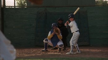 Movie still from “The Bad News Bears” (1976), directed by Michael Ritchie – A baseball player holding a bat on top of a baseball field; Wide shot, Over the shoulder angle