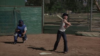 Movie still from “The Bad News Bears” (1976), directed by Michael Ritchie – A young boy swinging a baseball bat at a game; Wide shot, Over the shoulder angle