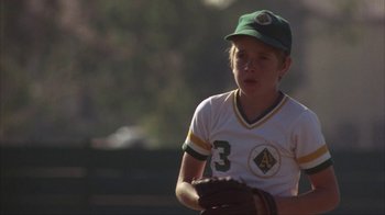 Movie still from “The Bad News Bears” (1976), directed by Michael Ritchie – A young baseball player is holding a ball in his hand; Medium shot, Low angle