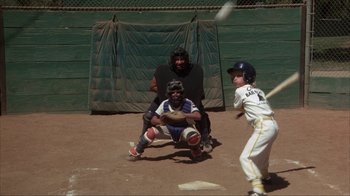 Movie still from “The Bad News Bears” (1976), directed by Michael Ritchie – A little league player swinging at a pitch; Wide shot, High angle