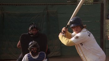 Movie still from “The Bad News Bears” (1976), directed by Michael Ritchie – A man holding a baseball bat while standing on a field; Medium shot, Over the shoulder angle