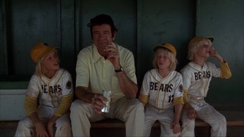 Movie still from “The Bad News Bears” (1976), directed by Michael Ritchie – A group of young baseball players sitting next to each other; Medium shot, Low angle