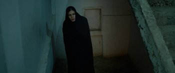 Movie still from “Holy Spider” (2022), directed by Ali Abbasi – A woman wearing a black robe standing in an empty room; Medium shot, High angle