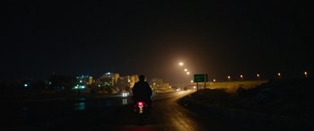 Movie still from “Holy Spider” (2022), directed by Ali Abbasi – A man riding a motorcycle down a street at night; Wide shot, Low angle