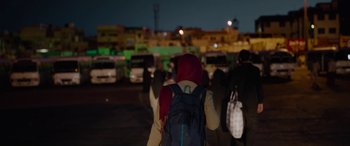 Movie still from “Holy Spider” (2022), directed by Ali Abbasi – A group of people walking down a street at night; Medium shot, Over the shoulder angle