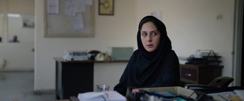 Movie still from “Holy Spider” (2022), directed by Ali Abbasi – A woman sitting at a desk wearing a black veil; Close Up shot, Over the shoulder angle