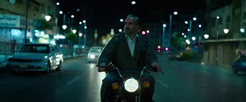 Movie still from “Holy Spider” (2022), directed by Ali Abbasi – A man riding a motorcycle down a street at night; Medium shot, Low angle