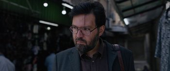Movie still from “Holy Spider” (2022), directed by Ali Abbasi – A person with a beard wearing glasses; Close Up shot, Over the shoulder angle